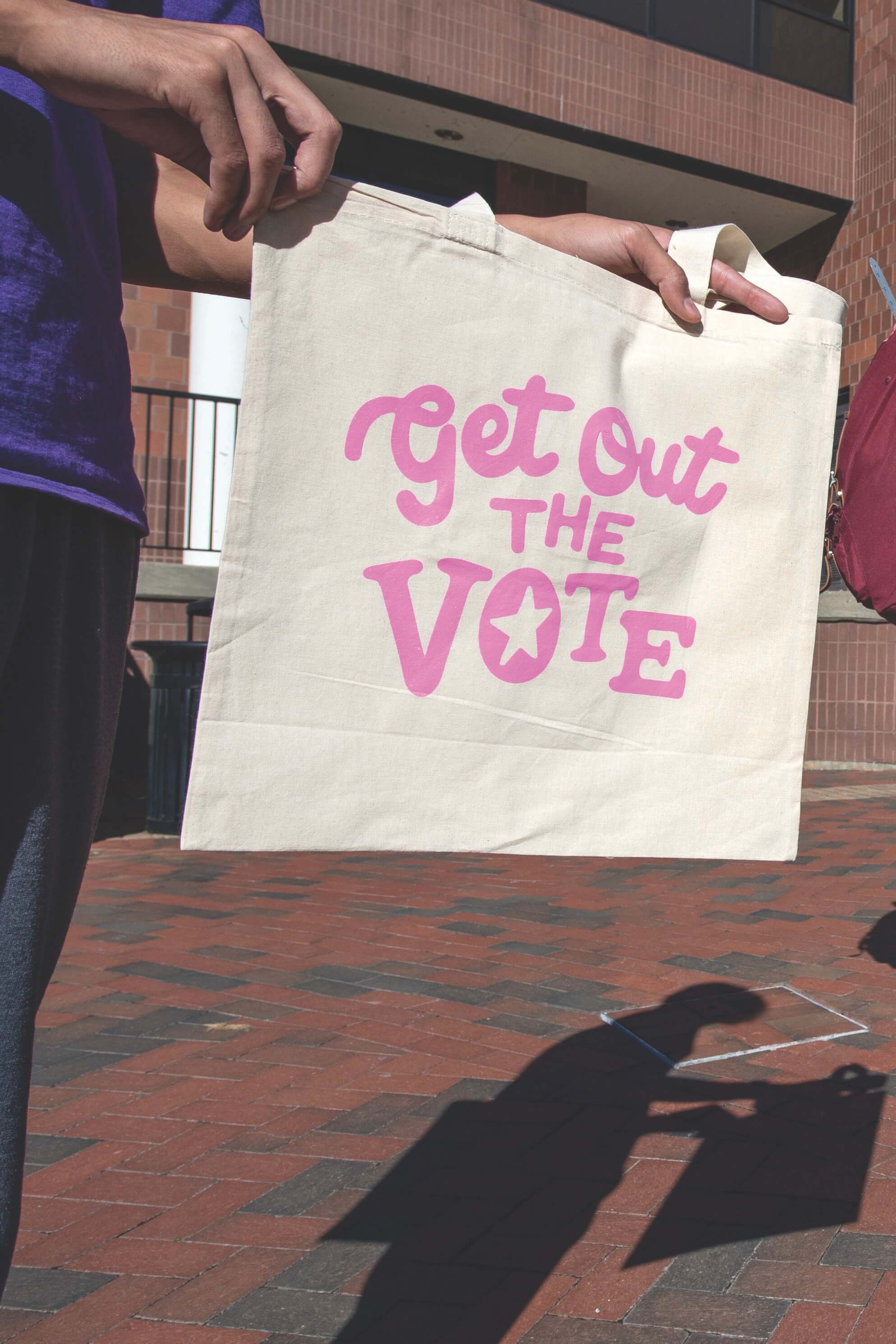 A student holds a Get Out the Vote tote bag in front of the VCU Student Commons