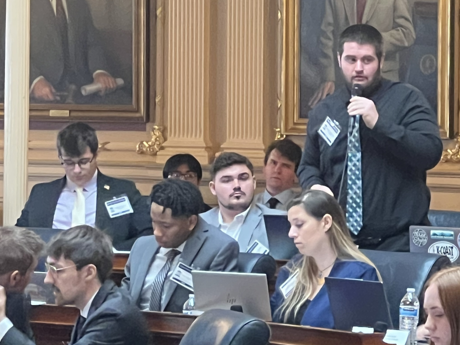 Bridgewater College Delegates (left to right) Ethan Thee, Dylan Shifflet, and Collin Nicholson. Delegate Nicholson is standing, speaking into his microphone.