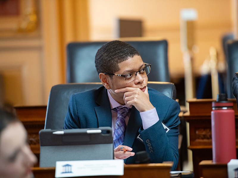 A student sitting in a chair in the Virginia State Capitol chambers