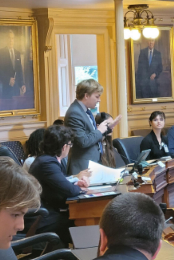 Republican Delegate Aaron Ress speaking on the House Bill  318 and how it would impact the Wildlife Conservations in  Virginia (Ress standing, mike in right hand, looking down and  reading out the claim).