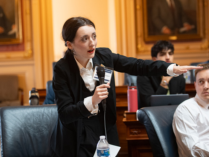 A student speaks into a microphone and points